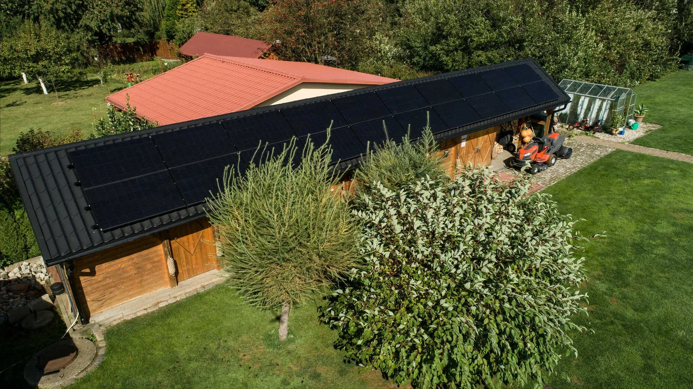 Nowoczesne panele fotowoltaiczne full black Selfa na dachu drewutni - widok z drona