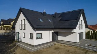 Czarne panele fotowoltaiczne i biały dom